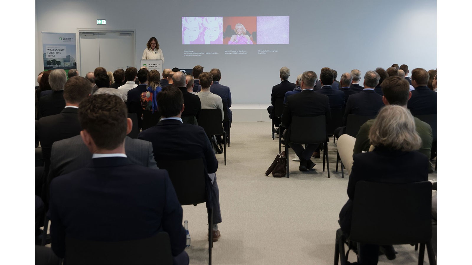 Vortrag vor Publikum in Reihenbestuhlung